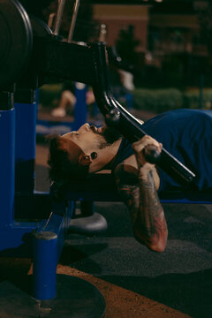 Muscular man training hard on outdoor equipment at night