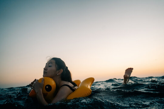 Enjoying a Sunset Swim With a Yellow Inflatable in the Ocean