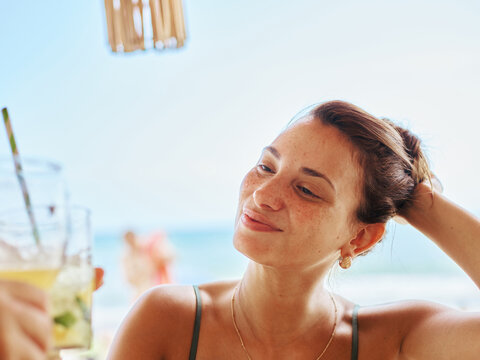 Smiling Woman Enjoying a Refreshing Drink at the Beachside Cafe