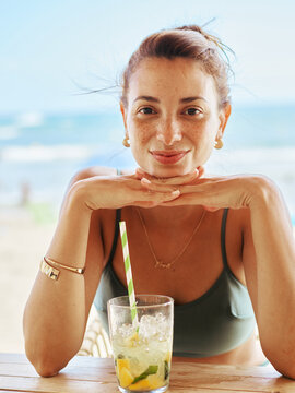Woman Enjoying a Refreshing Drink at a Beachside Bar During Summer