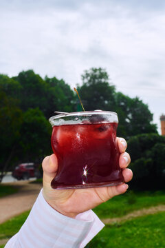Bright red drink in hand in bright park