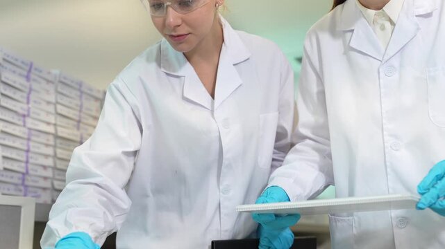 Clinical pathologists evaluating diagnostic biomaterial specimens on illumination interface. Medical specialists conducting clinical trial assessments.