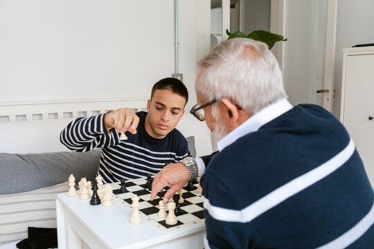 Young Man Plays Chess With Senior Family 