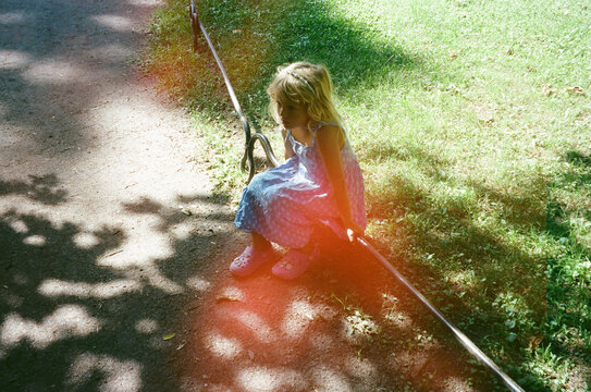 Young Girl Sitting on a Park Path During a Sunny Day