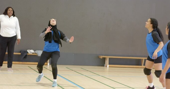 Serve spurring teammate bumping to hijab setter raising arms to spike rival returning in gym drill