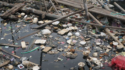 Various types of trash are scattered along the river towards the beach. This trash is dominated by non-biodegradable waste such as plastic and Styrofoam.
