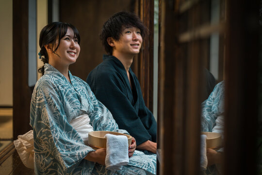 Couples in yukata enjoying the cool evening breeze on the veranda of a hot spring inn, temple lodging, or traditional Japanese house