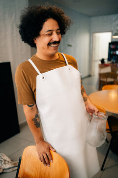 Smiling Person Wearing an Apron in a Modern Kitchen Setting