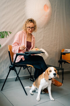 Woman Enjoying a Meal at a Cafe With a Beagle Companion