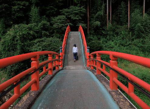 Woman crosses the vermilion red Taikobashi bridge.