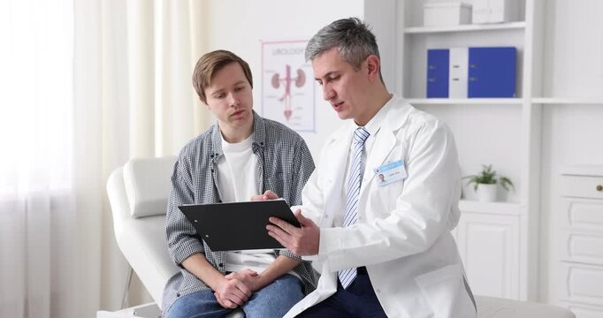 Urologist with clipboard consulting patient on medical couch in clinic