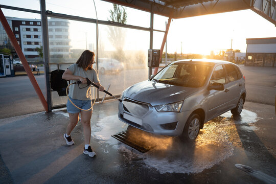 Woman rinsing car with water hose