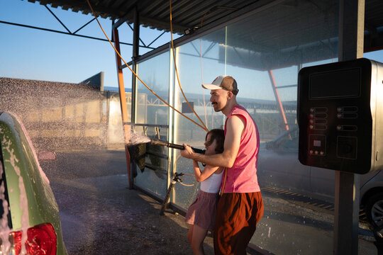 Joyful family car wash at sunset