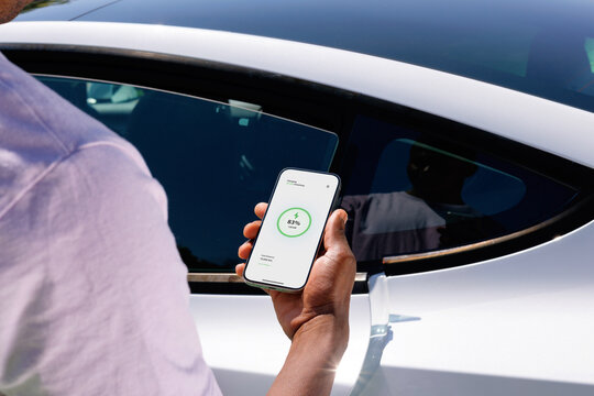 Phone Showing EV Charging Beside Electric Car