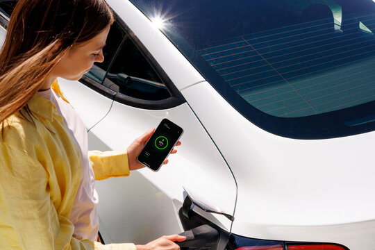 Woman Monitoring Electric Car Charging on Smartphone an app