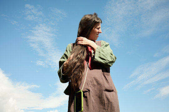 Woman with long hair standing outdoors under a blue sky