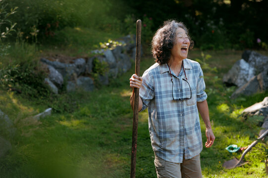 Smiling woman enjoying the outdoors holding a stick on a sunny day