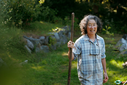 Smiling woman tending garden with wooden rake