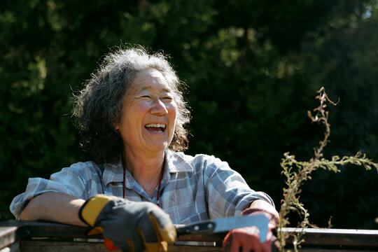 Joyful senior woman gardening outdoors with tools on a sunny day