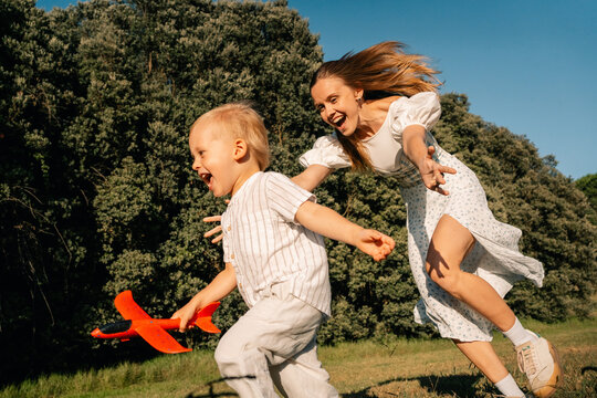 Mother and Child Joyfully Playing With Toy Airplane in a Field