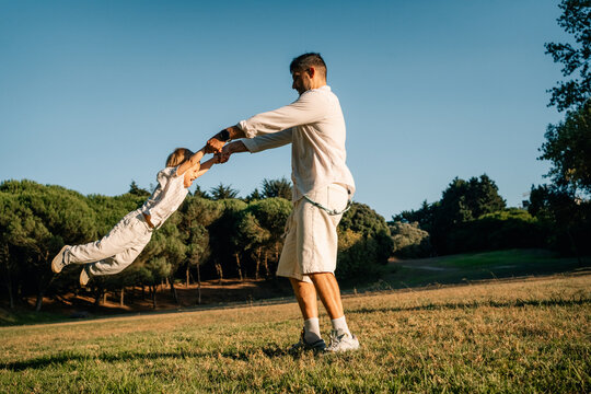 Father Enjoys Playful Moment With Child in Sunny Park Setting