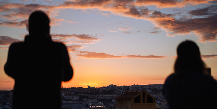 Silhouettes of people taking photos of the sunset in Lisbon