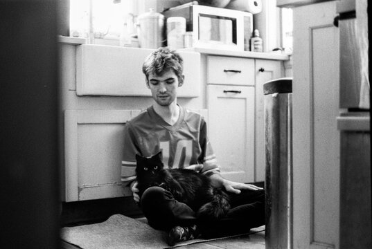 Teen sits on floor with cat