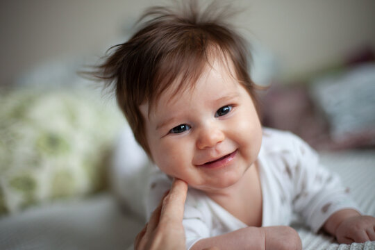 Smiling Baby with Messy Hair on Bed
