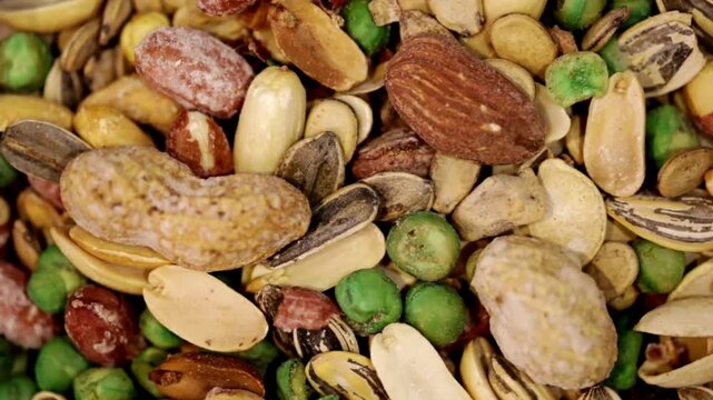 Top view of assorted nuts and seeds including almonds, walnuts, sunflower and pumpkin seeds forming a textured natural food background with rich earthy tones and organic detail.