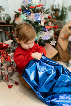 A baby opening a Christmas gift