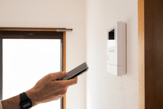 Man using smart home control panel with smartphone