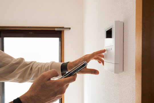 Man using smart home control panel with smartphone