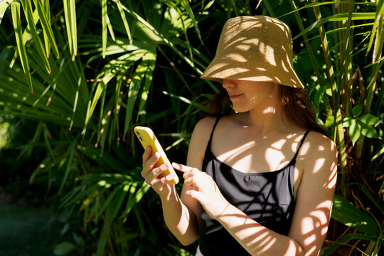 Woman using smartphone in tropical sunlight