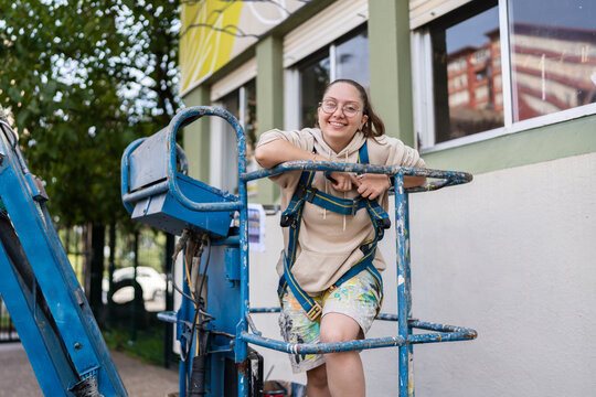 Muralist taking a break on a hydraulic platform during work