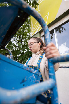 Female painter working on cherry picker is painting a building wall