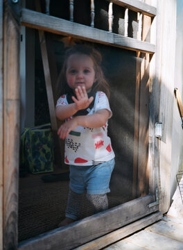 Portrait of a cute toddler pushing on a rustic screen window