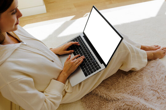 Woman working remotely from home using laptop with blank screen