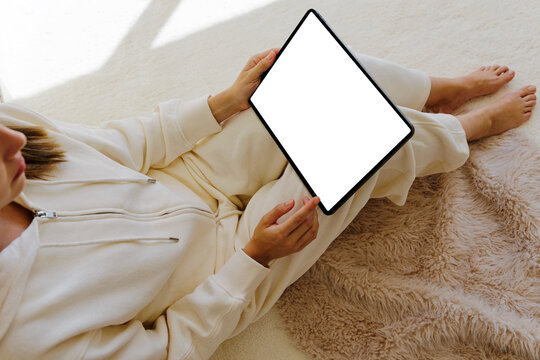 Woman relaxing on carpet using digital tablet with blank screen