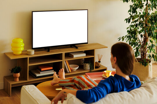 Woman relaxing on sofa watching smart tv with blank screen at home