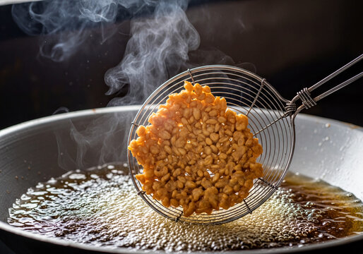 Authentic golden-brown rice cracker frying in hot bubbling oil, expertly lifted with a skimmer creating steam in a dimly lit kitchen.