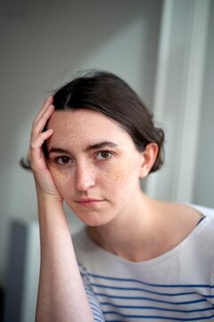 Young Woman With Freckles Poses Thoughtfully Indoors