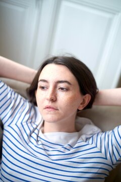 Young Woman Relaxing Indoors With a Thoughtful Expression