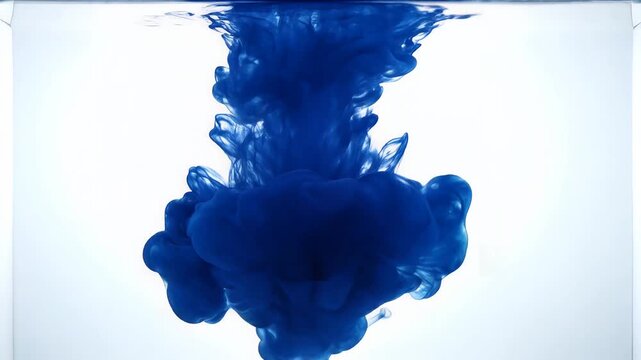 Blue ink dropping into clear water on white background for abstract design