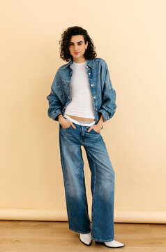 Queer model posing in denim outfit and white boots