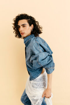 Queer model posing in denim jacket and lace skirt