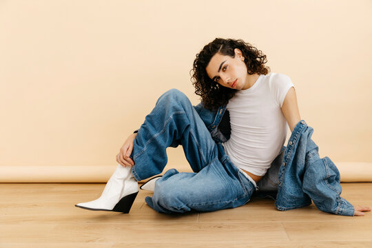 Queer model posing in denim outfit and white boots