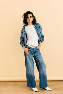 Queer model posing in denim outfit and white boots