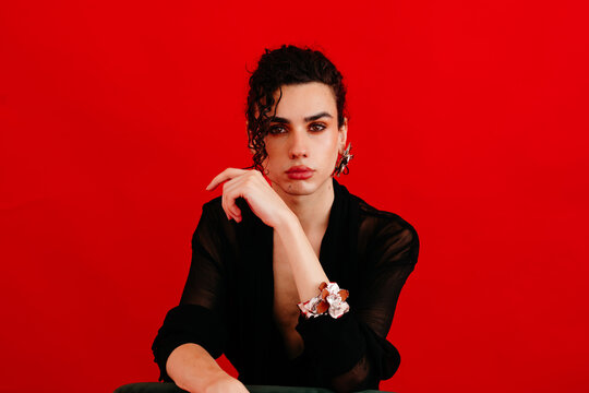 Queer man posing confidently with red background