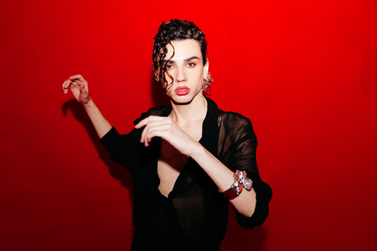 Queer man posing  on red background