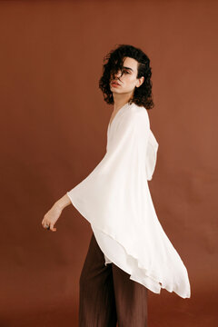 Queer man posing in white flowy fashion top